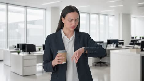 Indian-female-manager-waiting-for-someone-and-drinking-coffee