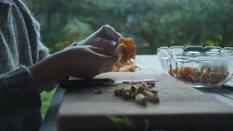 Female-hands-cleaning-golden-chanterelle-mushrooms-on-wooden-board-outside