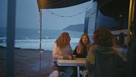 group women talking camp terrace spending weekend evening on ocean shore.