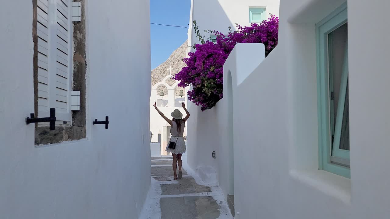 chica turista bailando y sintiéndose emocionante caminando en la hermosa ali en santorini, grecia