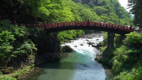 el puente rojo de shinkyo, que cruza un río que fluye en nikko, japón