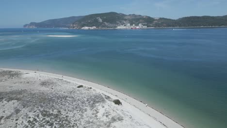 aerial view of beach with some people enjoying the turquoise water and ocean on a sunny day with a bright sky