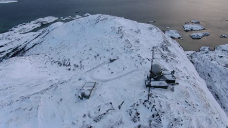 drone view in tromso area in winter flying over a snowy mountain peak and into the ocean in norway