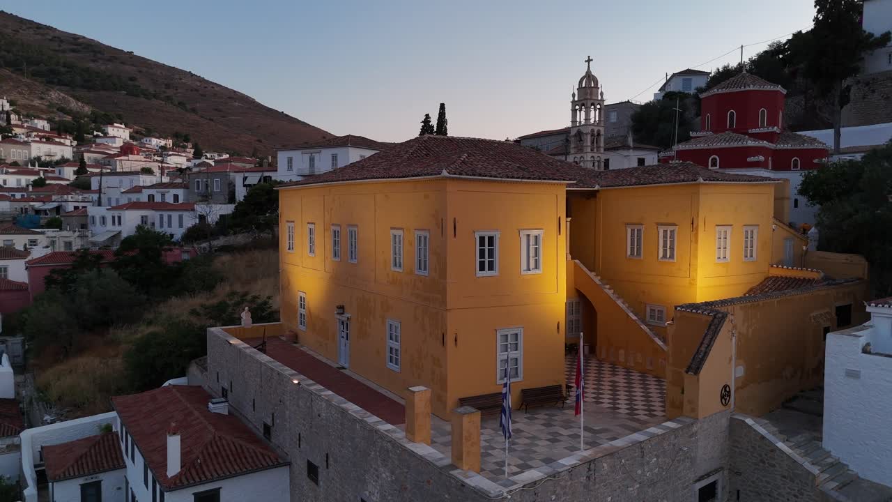 Vista aerea dello storico edificio giallo sull'isola di Hydra, Grecia, al crepuscolo