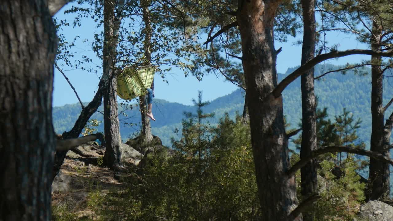 Person relaxing in a hammock in a forest