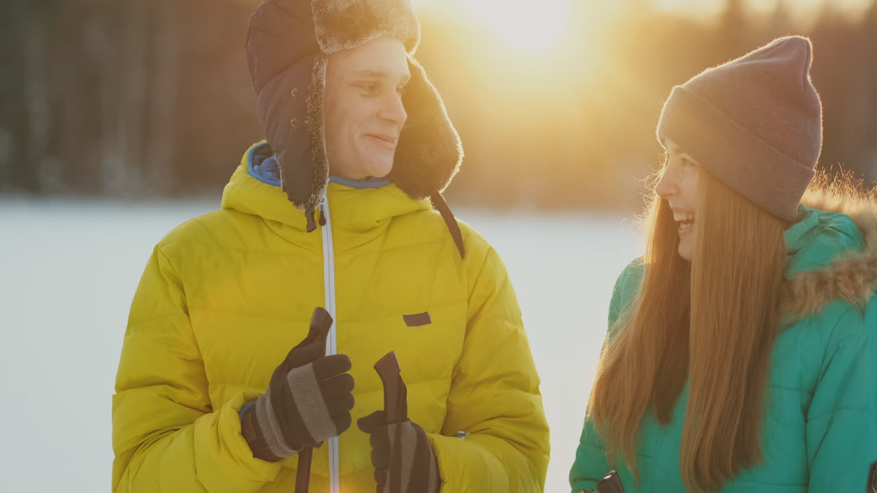 A man embraces a woman standing in the woods at sunset after a winter walk on skis. St. Valentine's Day. Romance and warm feelings of lovers. Slow motion