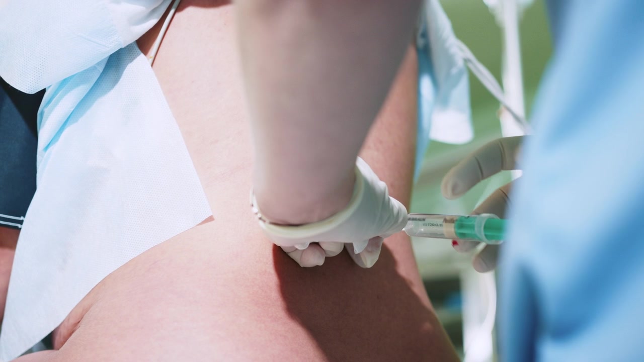 마취과 의사가 척추 마취를 위해 주사기에 약물을 채우고 환자에게 주사할 준비를 합니다.