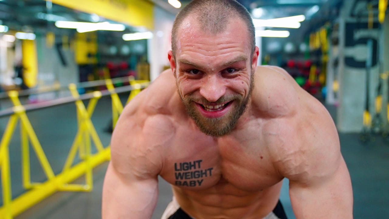 Uomo culturista muscoloso sorridente e in posa in palestra