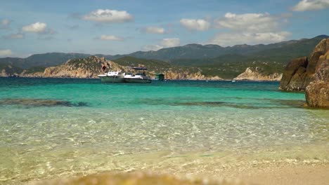 Man-jumps-from-motorboat-into-crystal-clear-emerald-sea-water-in-tropical-bay