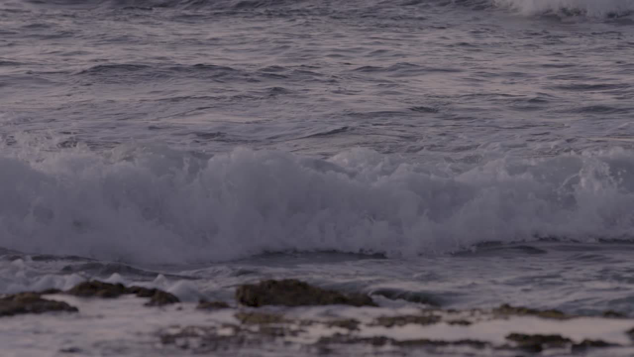 медленное панорамирование вдоль пляжа на гавайях, когда волны накатывают на берег на закате солнца