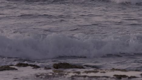 slow pan along the beach in hawaii as waves roll up onto the shore at sunset