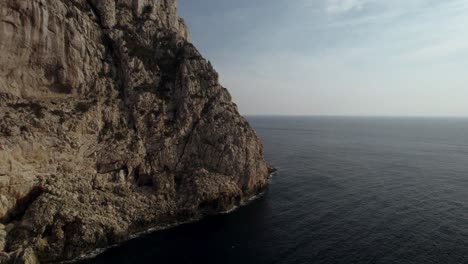 aerial shot of the massive cliffs and a dark calm mediterranean sea surface