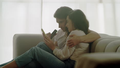 closeup pareja feliz viendo teléfonos móviles en casa. retrato de personas relajadas