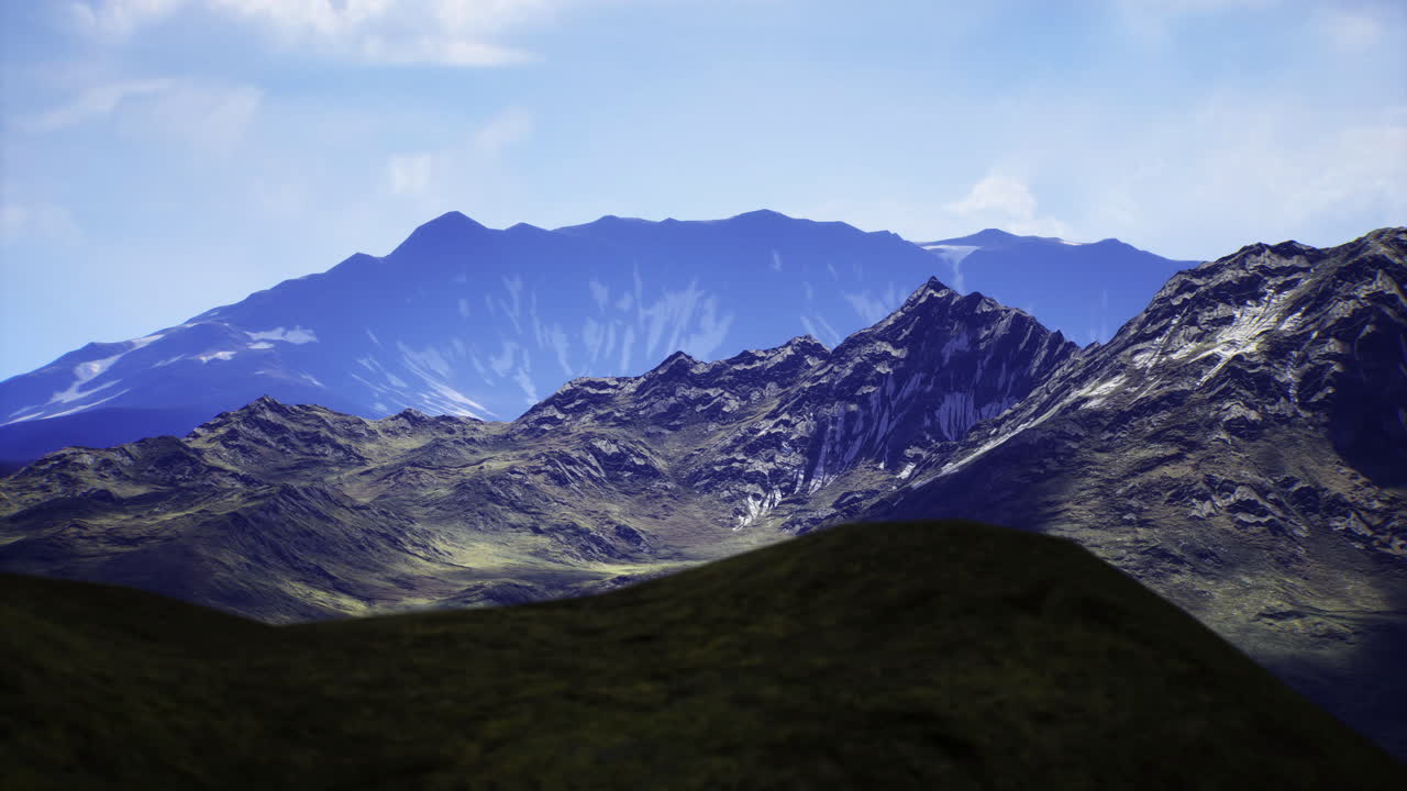 Majestic mountain range with blue sky and rolling green hills in daylight
