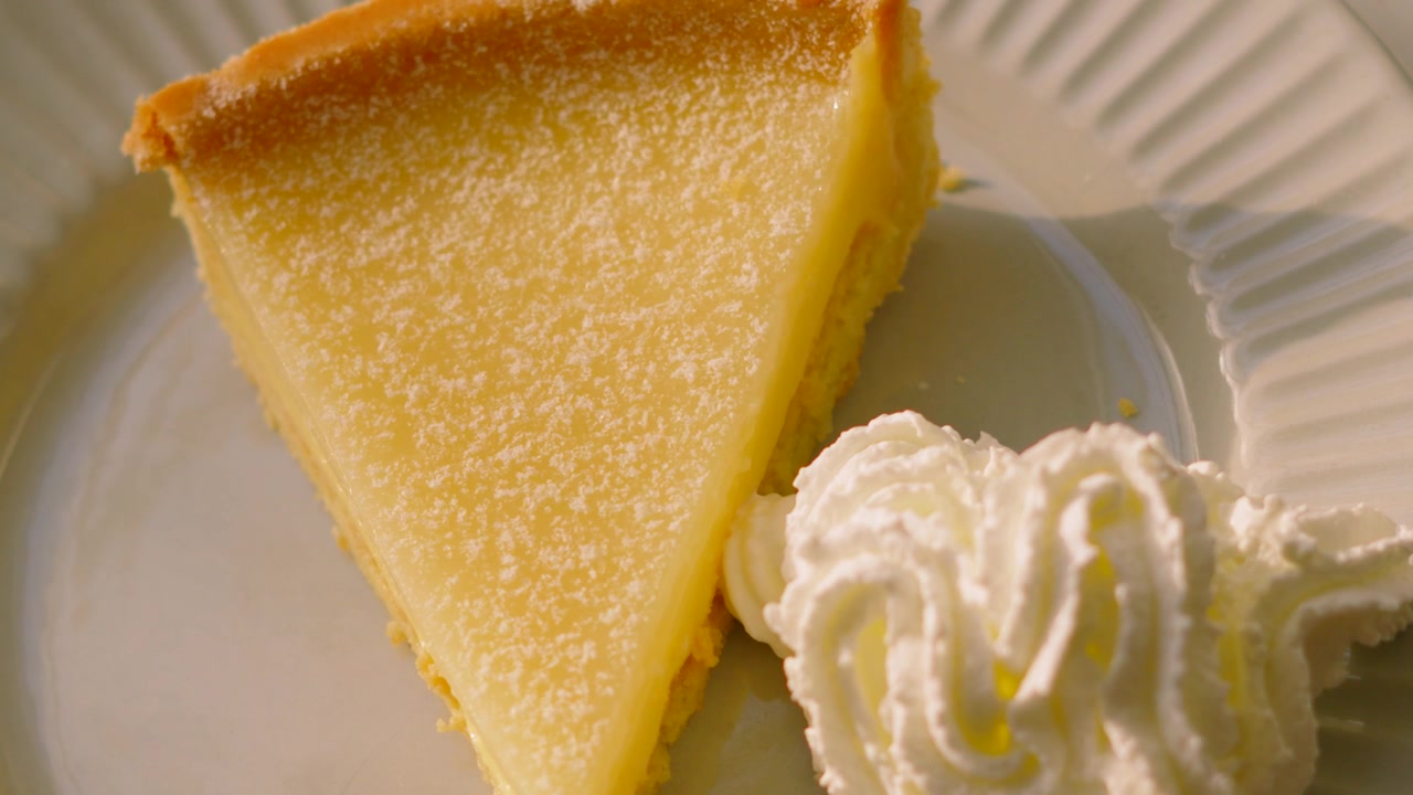 Pohled shora na klasický francouzský Tarte au Citron na talíři se šlehačkou. Ideální pro aplikace s jídlem, montáže pro sociální média, promo akce luxusních restaurací, videa s dezertní tematikou. 4K.