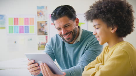 Profesor-Y-Estudiante-En-El-Aula-De-La-Escuela-Usando-Una-Tableta-Digital-Juntos