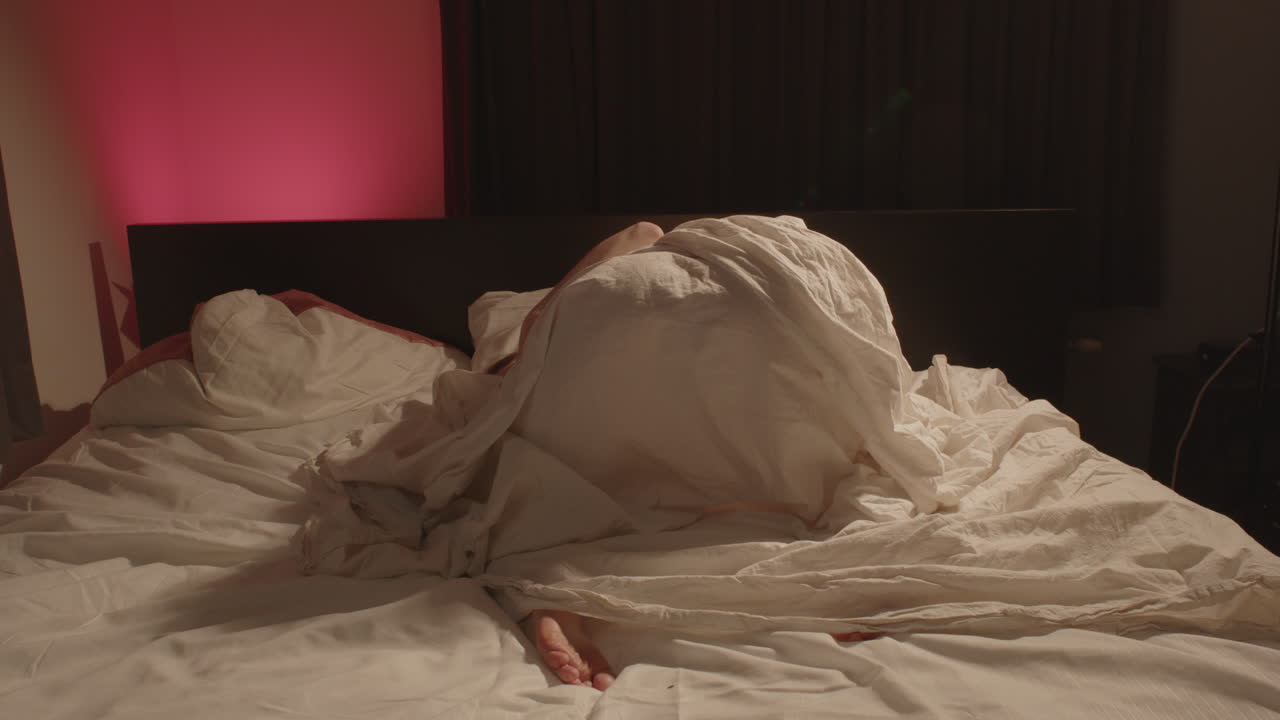Ampia veduta della schiena di una bella donna che posa con grazia a letto e si flette dolcemente al rallentatore.