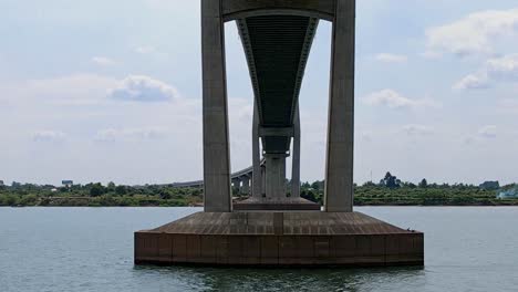 Aerial-forward-flight-under-gigantic-Tsubasa-Bridge-and-above-Mekong-River-during-sunny-day-at-border-checkpoint-of-Cambodia-and-Vietnam