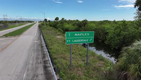highway sign directing to naples and fort lauderdale amidst lush florida landscape