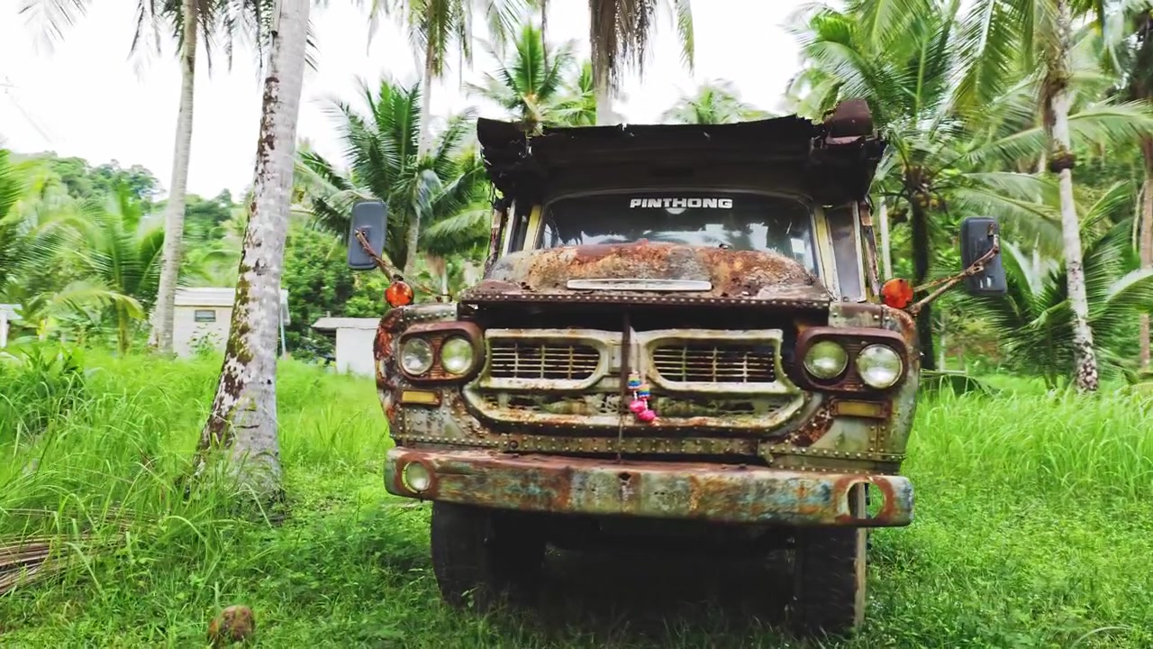 Altes Auto zwischen Palmen in Thailand geparkt