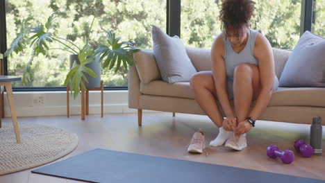 tying shoes, plus size woman preparing for workout on yoga mat at home