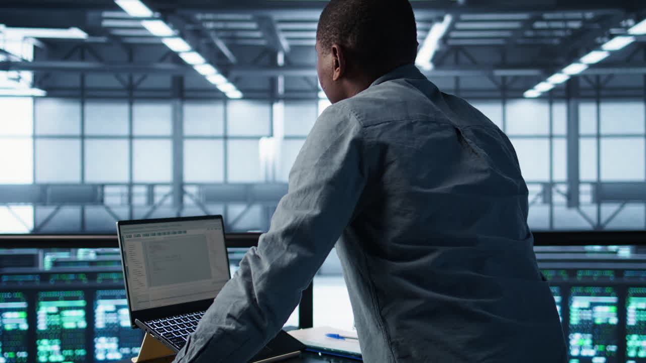 Technician in data center using programming languages on laptop