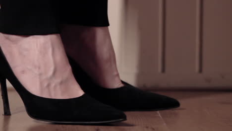 Close-up-shot-of-woman-walking-in-black-high-heels-shoes-on-wooden-floor