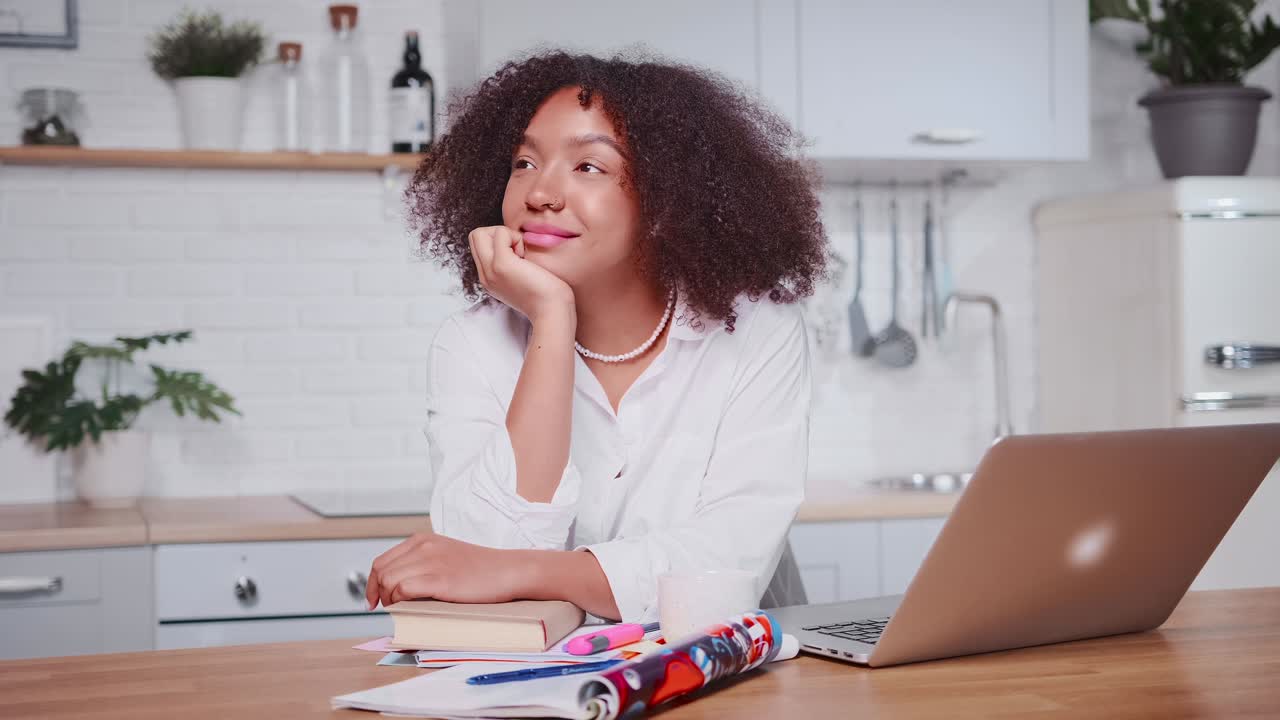Smiling african american woman dreaming of future success in cozy kitchen