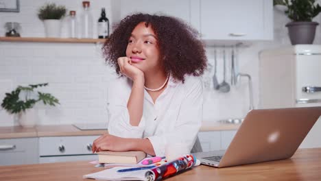 smiling african american woman dreaming of future success in cozy kitchen