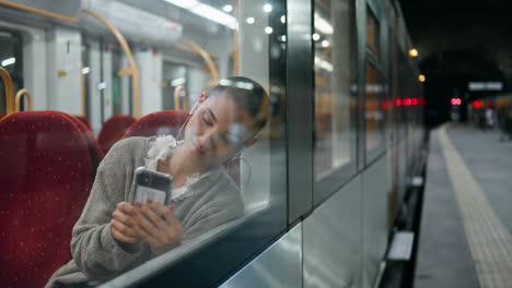 mujer usando un teléfono inteligente en un tren por la noche