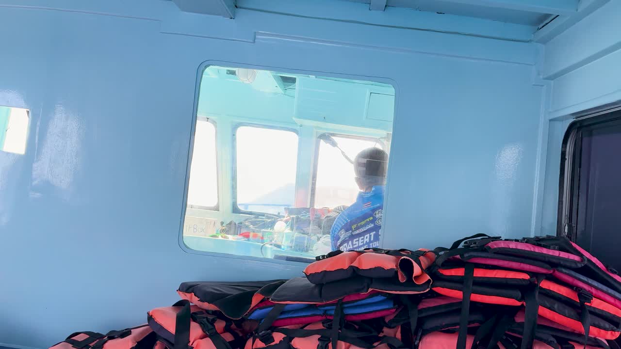 A calm boat ride in Phuket, Thailand, with life jackets visible inside the cabin. Bright daylight illuminates the scene