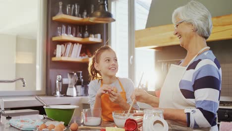 Happy-grandma-mixing-mixture-little-girl-standing-besides-her-4K-4k