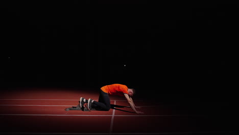 sprinter in starting blocks at night