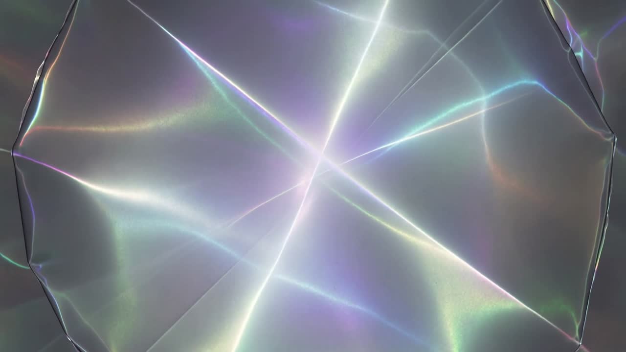 Shifting iridescent disc in studio showing line crossing center forming X rays and hue bands