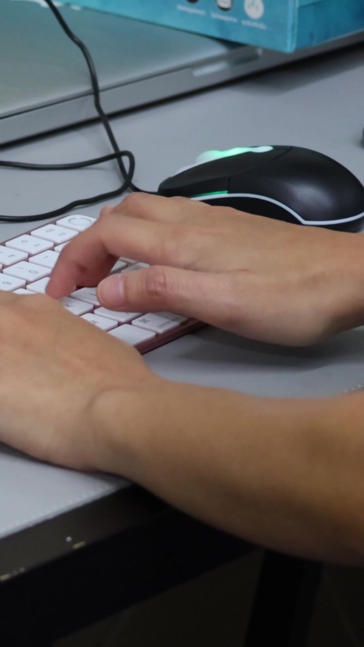 A person's hands are shown typing quickly on a white keyboard in a vertical crop.