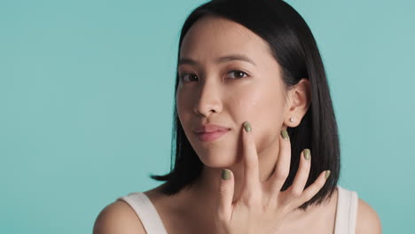 asian woman applying cream on her face.