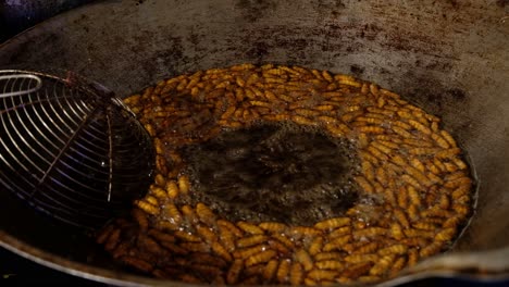 bamboo caterpillar deep frying in a wok at an asian street food stall