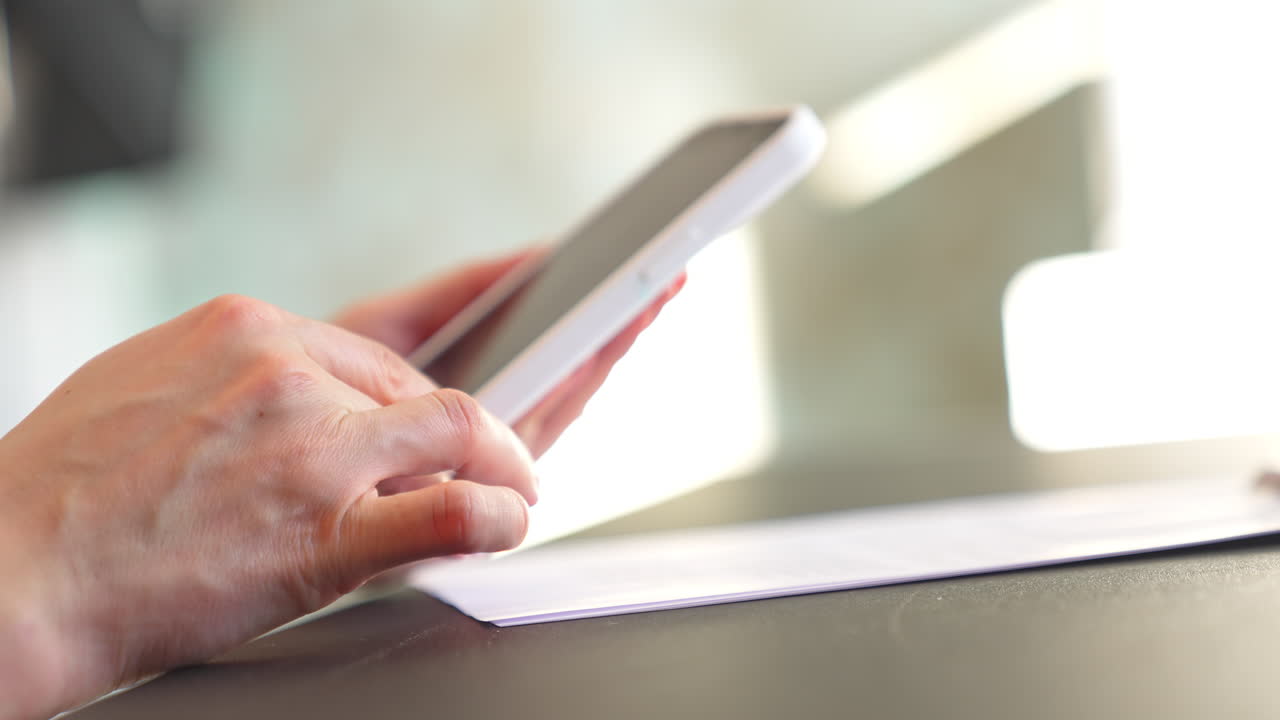 Woman presses gently on the telephone screen to take a picture of a document. Female hands rise the phone to look at the shot closer.