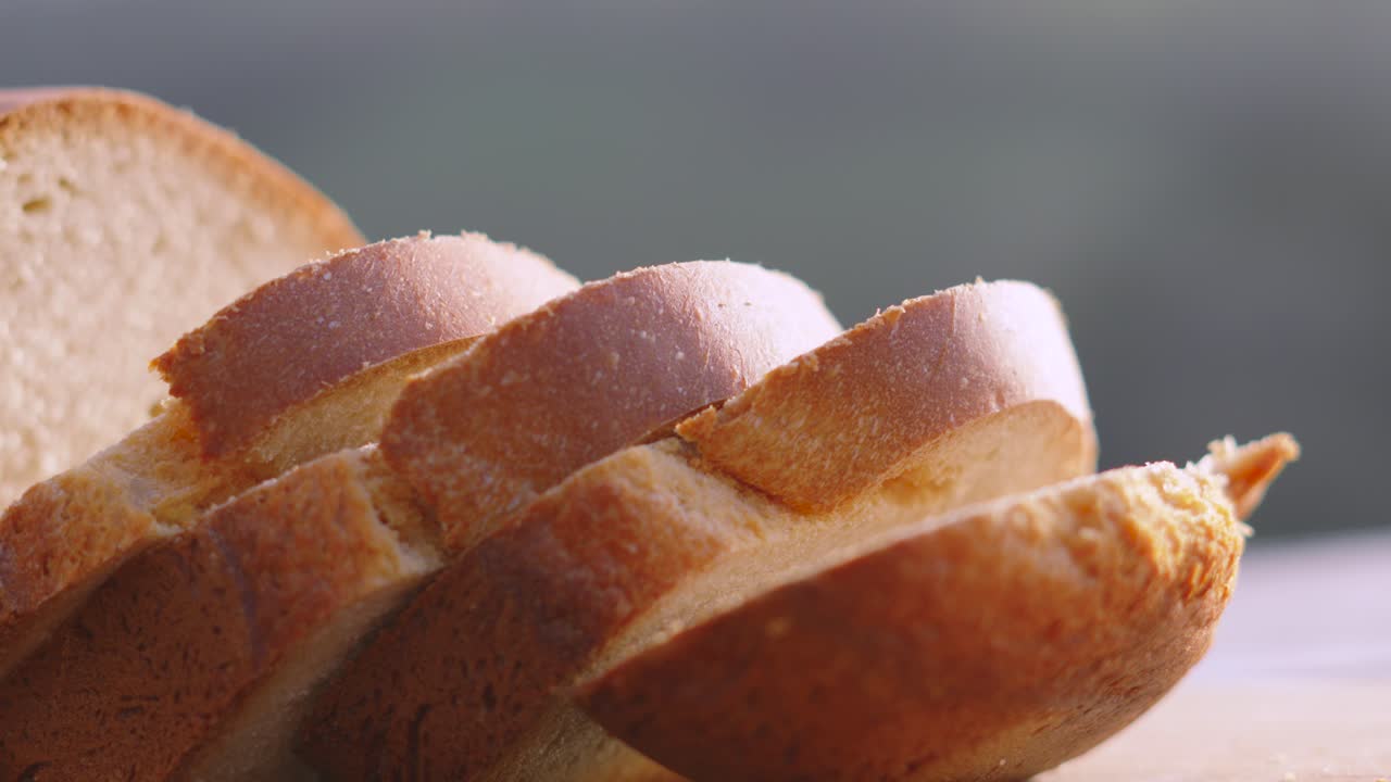 Slices of Freshly Baked Homemade White Bread on Wooden Chopping Board Outside in Natural Morning Environment with Sunlight. Home Baking Footage with Simple Healthy Ingredients 4K.