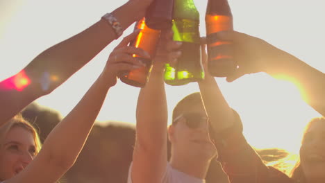 Los-Jóvenes-Levantan-Las-Manos-Y-Tintinean-Vasos-De-Cerveza-En-Botellas-De-Vidrio-Brillantes-En-La-Fiesta-De-Verano-Al-Aire-Libre.