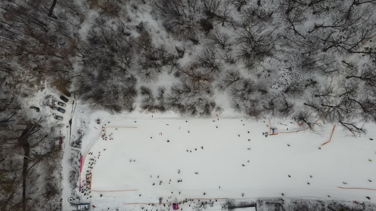 주말에 스키 리프트를 이용해 눈 슬로프에서 스키를 타는 스키어와 스노보더. 서리가 내린 겨울날 스키 리조트에서 스키어와 스노보더들과 함께 눈 덮인 슬로프 위로 날아가는 드론:드론 보기