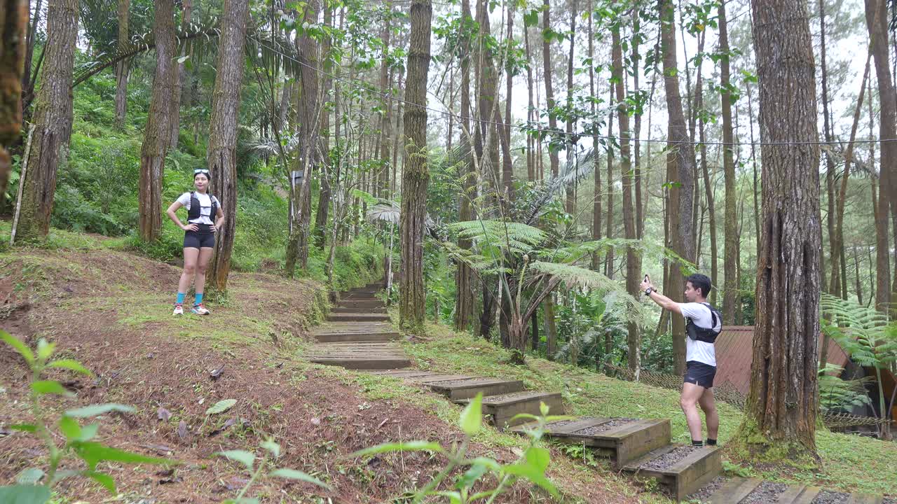 Asian couple taking photos during outdoor adventure in forest