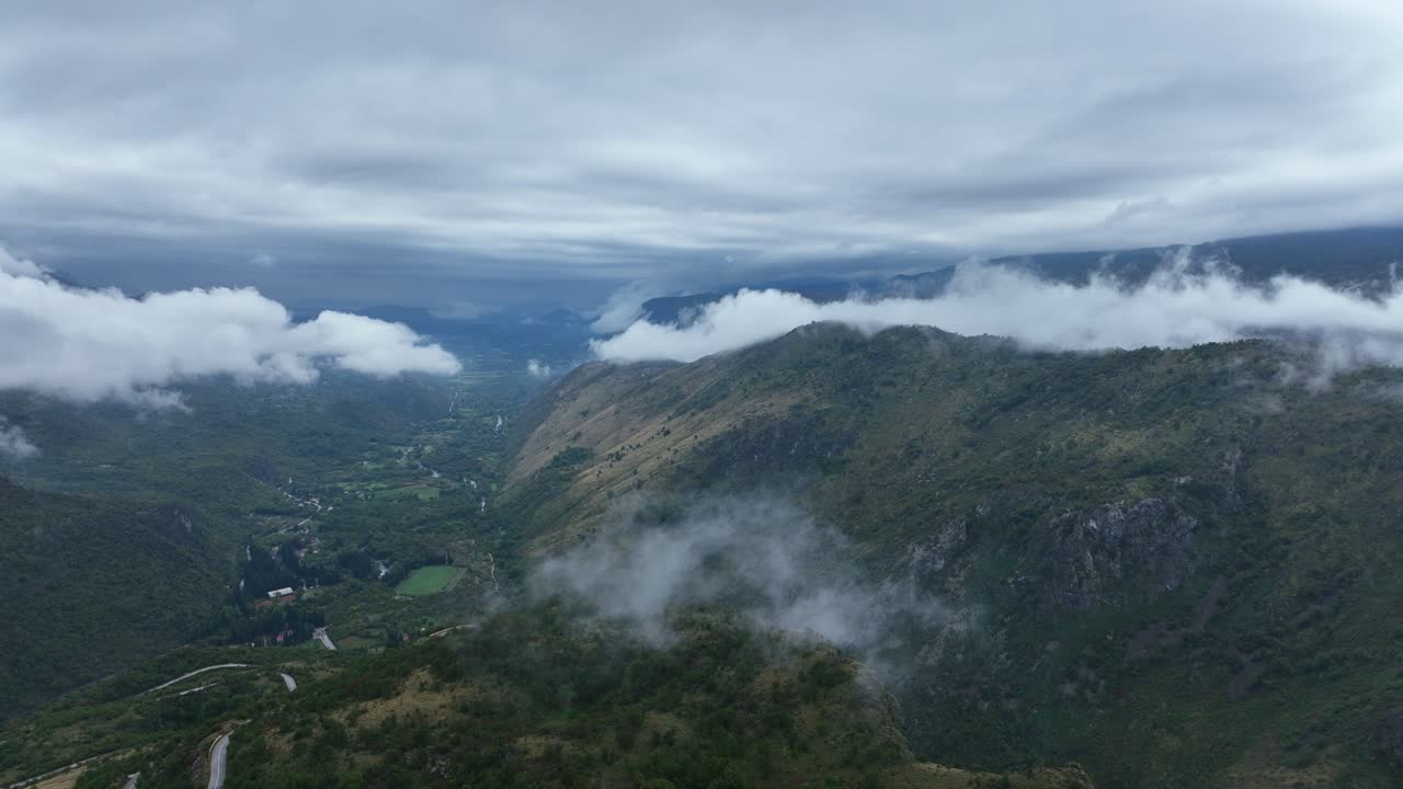 Establishing drone shot of mountains and clouds during the day in a rural zone near Cetinje, Montenegro