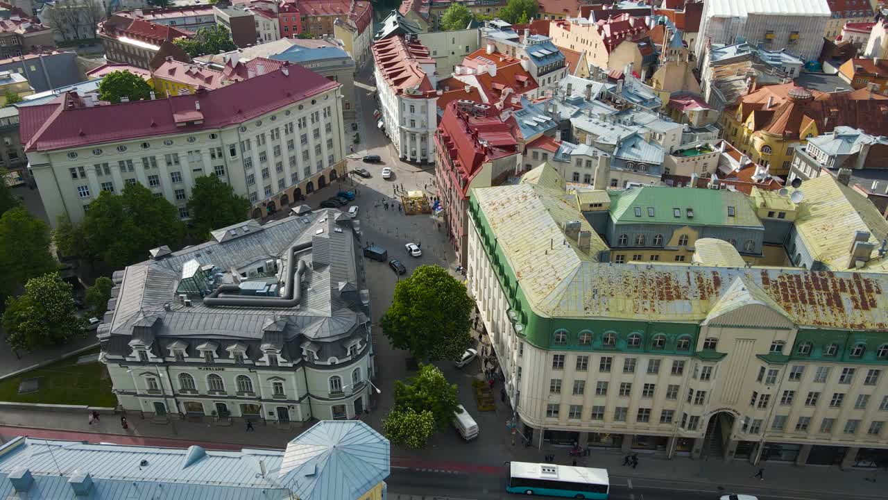 Aerial drone establishing footage of Tallinn central city medieval red historic buildings and rooftops with church towers and cobblestone roads visible, Tallinn harbor and Baltic sea in the background