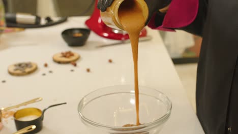 Close-up-of-hands-pouring-praline-dough-into-bowl