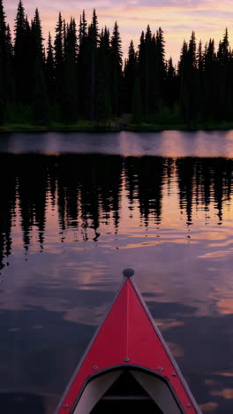 canoe on a calm lake with reflections of forest and a twilight sky