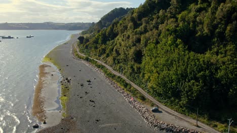 aerial view following the coastline of tenaun, golden hour in chiloe, chile