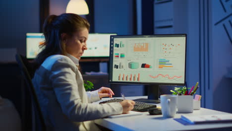 mujer ocupada trabajando por la noche delante de la computadora tomando notas