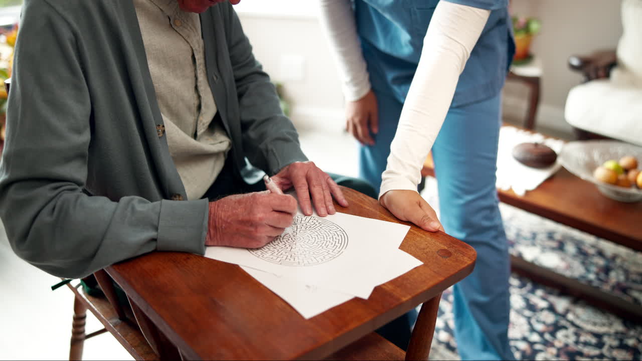 Elderly man completing maze puzzle with caregiver assistance