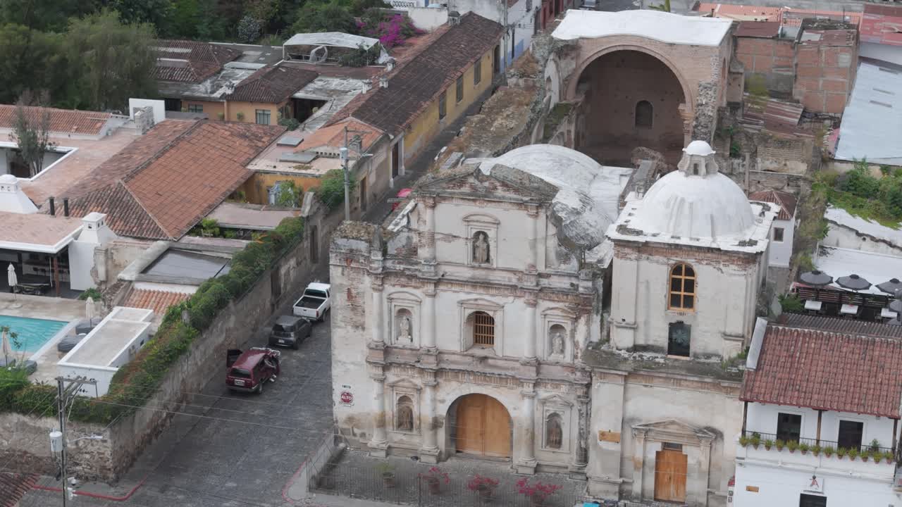vista aérea detallada de una ruina de una iglesia de la era colonial en antigua guatemala, rodeada de techos de azulejos y calles de adoquines